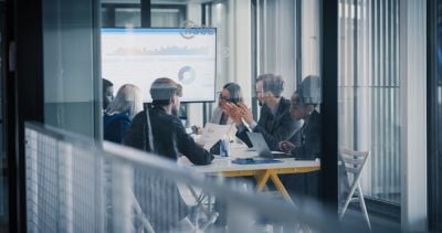 Business professionals discussing financial charts and reports around a conference table.