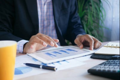 A man in a blue suit looks at a chart.