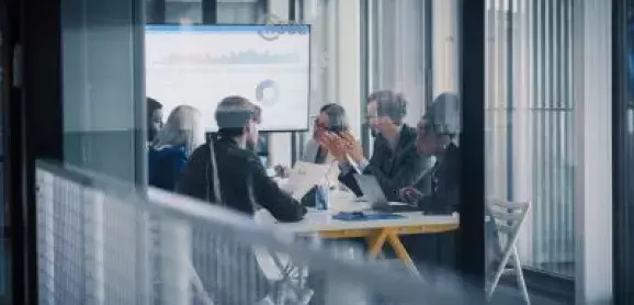Business professionals discussing financial charts and reports around a conference table.