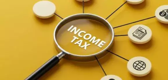 Magnifying glass highlighting “Income Tax” surrounded by financial icons on a yellow background.